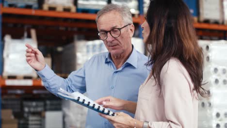 Mature-woman-and-man-analyzing-documents-in-the-warehouse